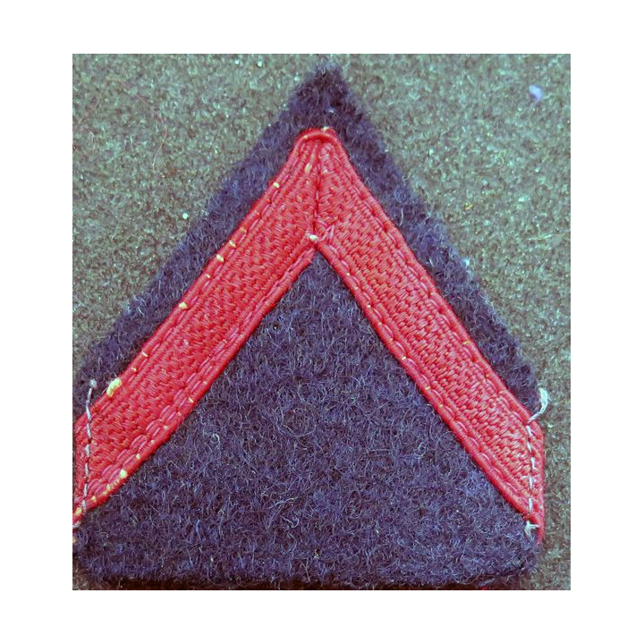 Galon de 1° Classe rouge sur tissu  bleu noir avec traces de colle