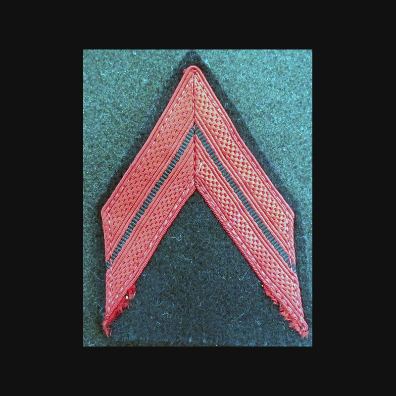 Galon de Caporal rouge sur tissu bleu noir avec traces de colle Galon de Caporal rouge sur tissu bleu noir avec traces de colle